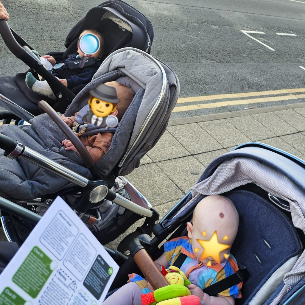 Three babies in prams (faces concealed by emojis) with the Treasure Trails pack visible